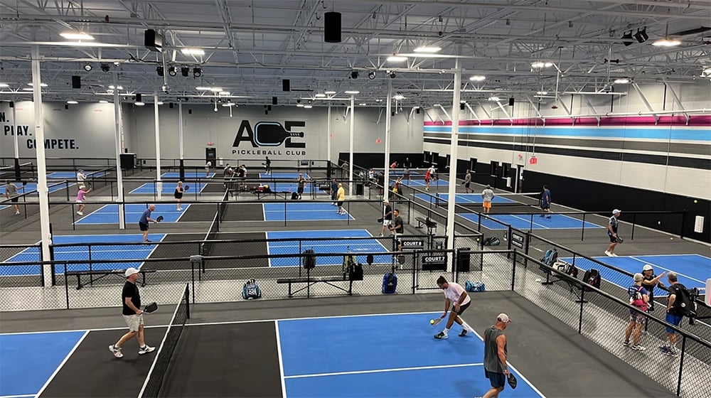image of people playing pickleball on several courts across a club