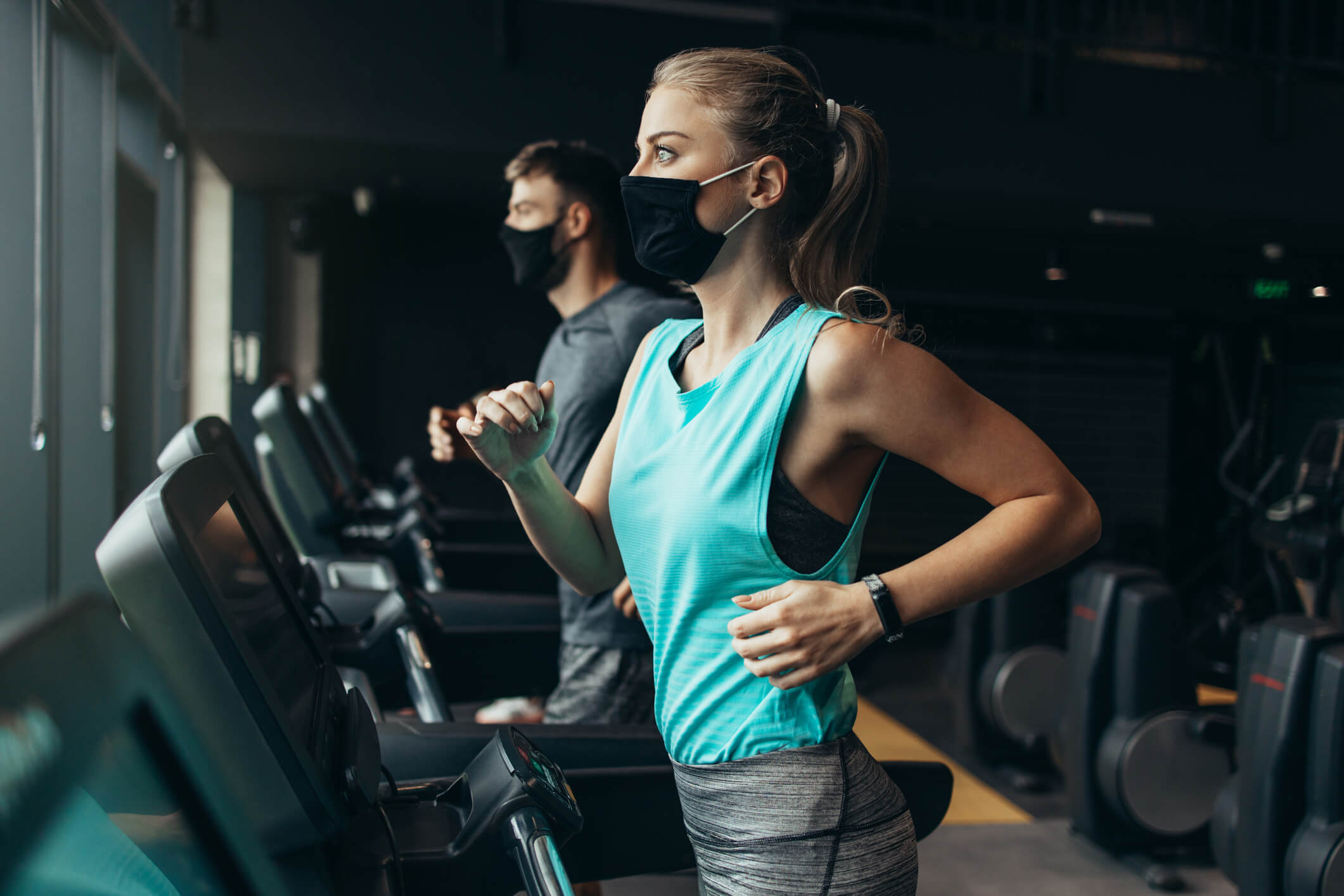 Woman and man on treadmill wearing masks