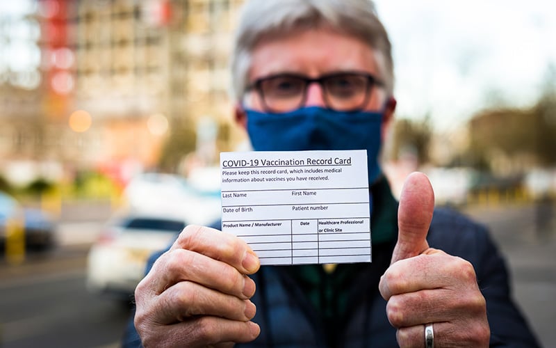 Man holding COVID-19 vaccine card