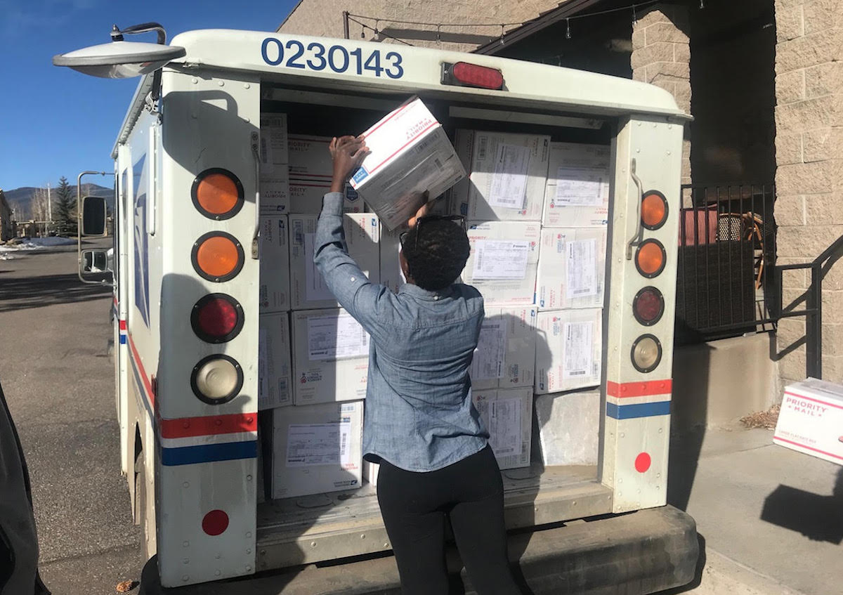 person putting packaged into USPS truck