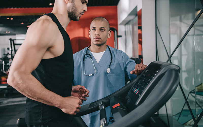 Doctor standing by man on a treadmill