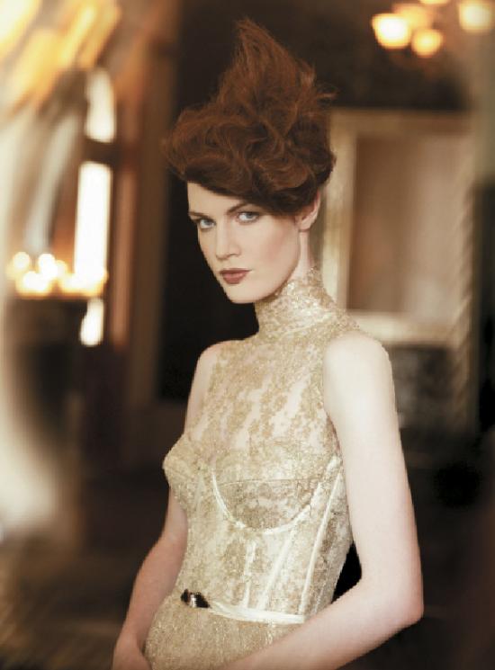 Side-swept fringe and textured, wavy hair that rises to a point at the crown area are the focus of this unique updo created by Blain.