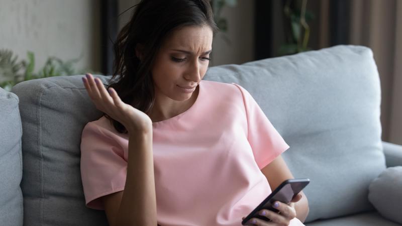 Woman looking in annoyance at AI images on her phone