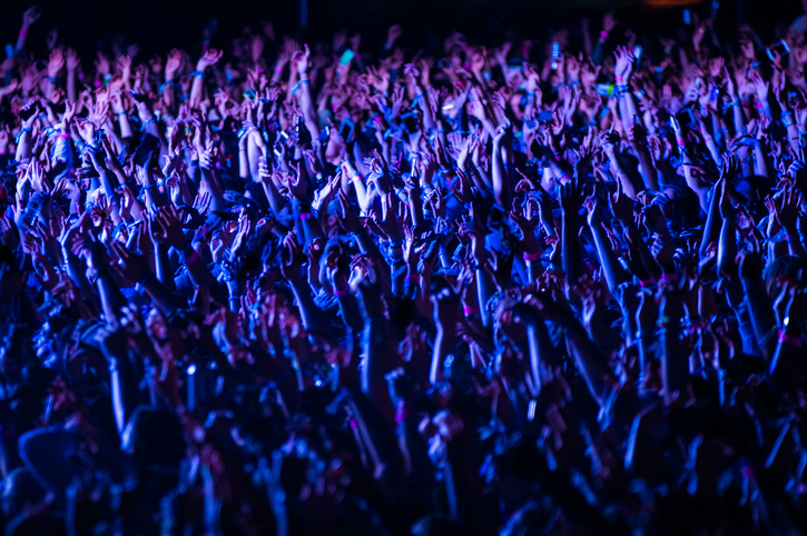 Crowd of people cheering at a music festival at night 