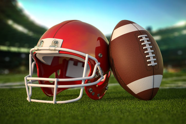 American football ball and helmet on the grass of football arena or stadium