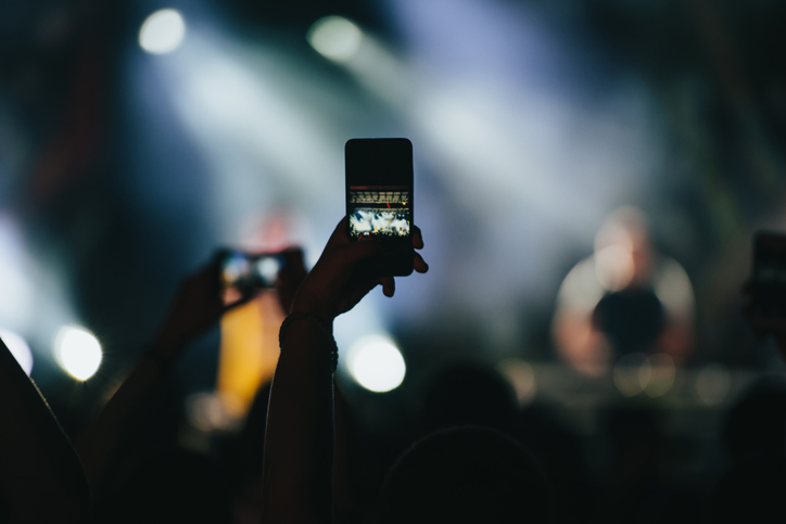 Fan in an audience on a concert recording on his smartphone