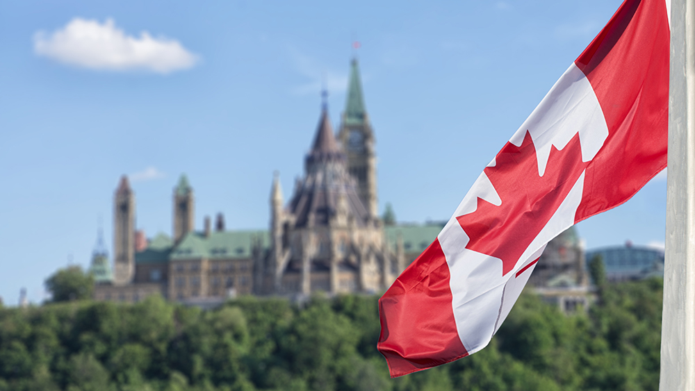 The Canadian flag with the Parliament Buildings in the background
