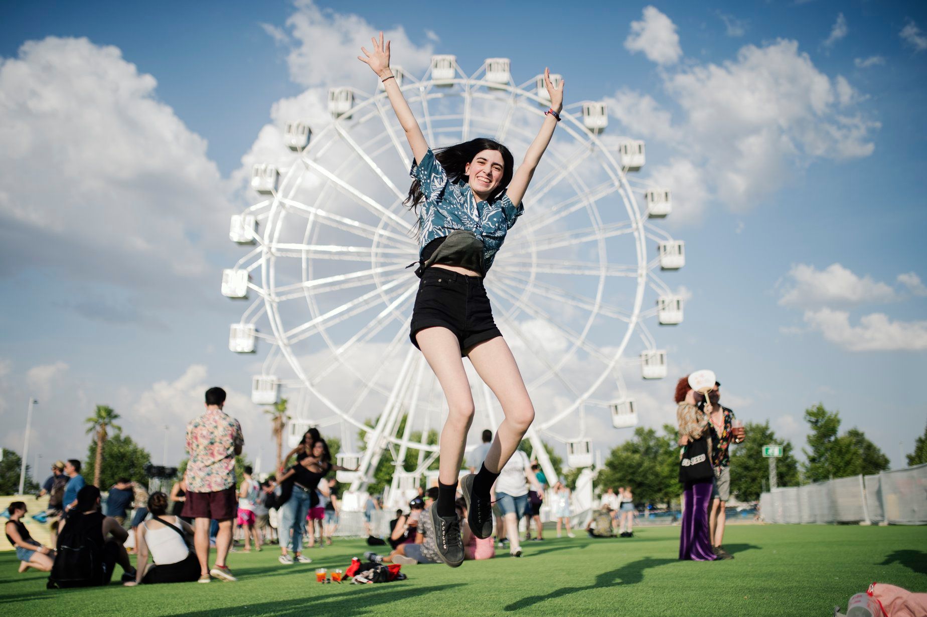 Girl jumping in front of ferris wheel
