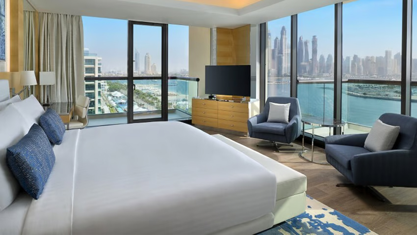 a hotel bedroom with the Dubai skyline visible through the windows