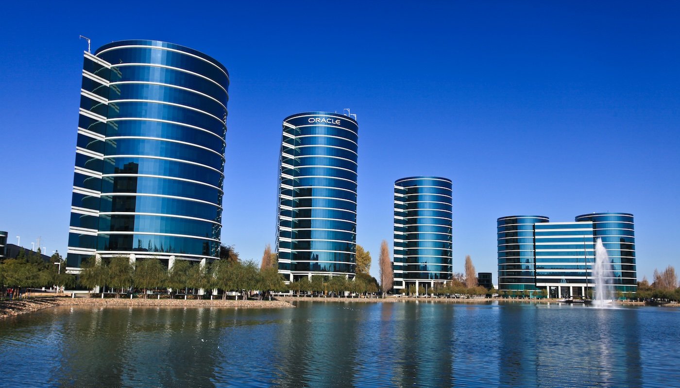 Oracles headquarters at Redwood Shores California featuring five cylindrical glass office towers reflected in a tranquil