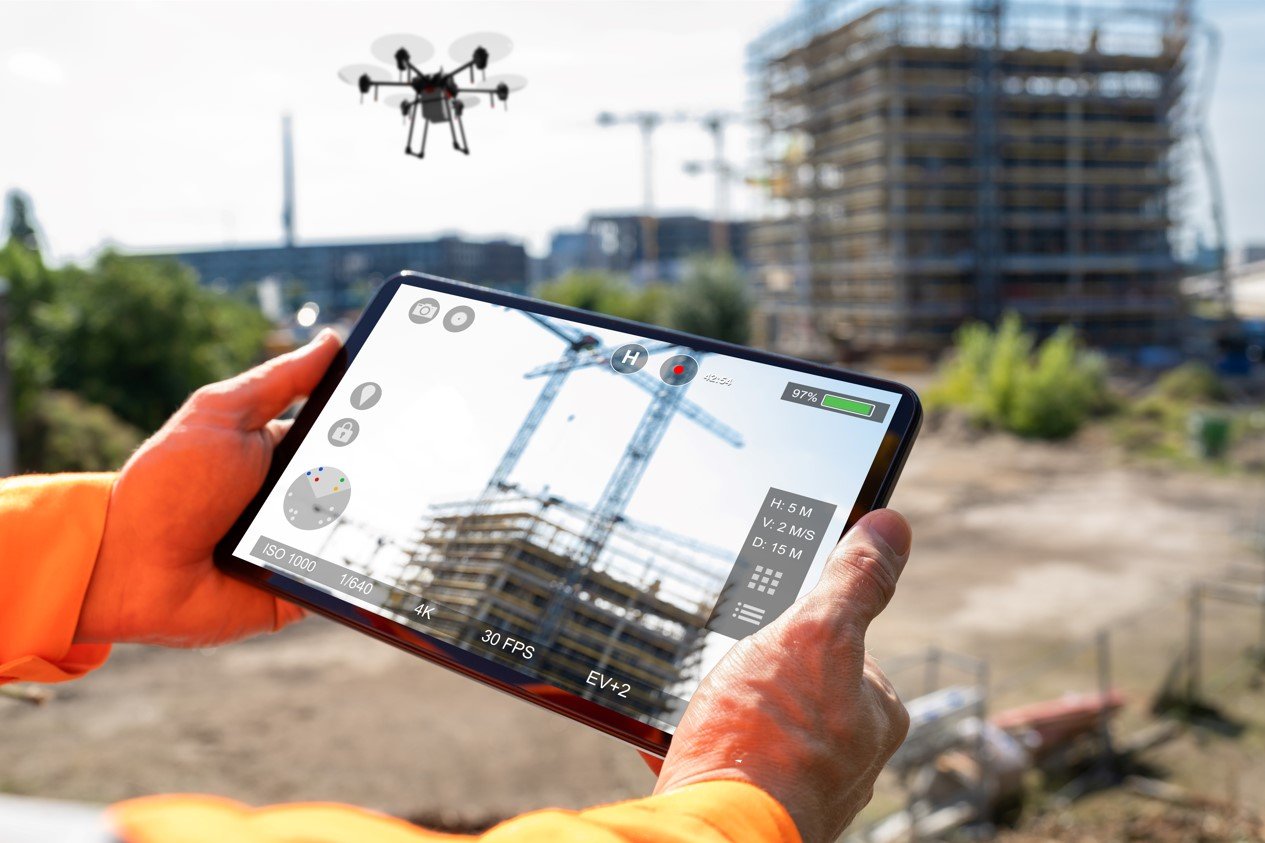 worker holds tablet to see what drone sees at construction siote