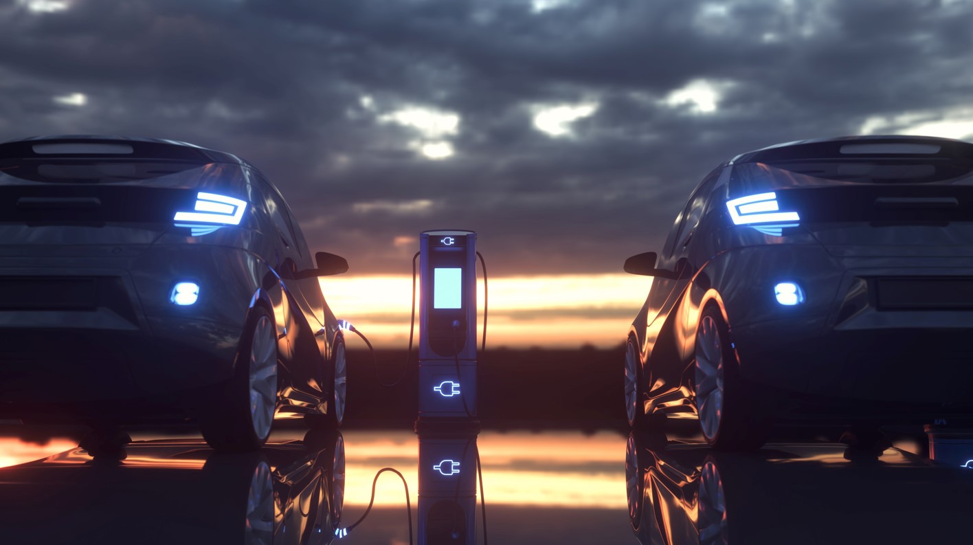 two vehicles shown charging at EV charger at sunset