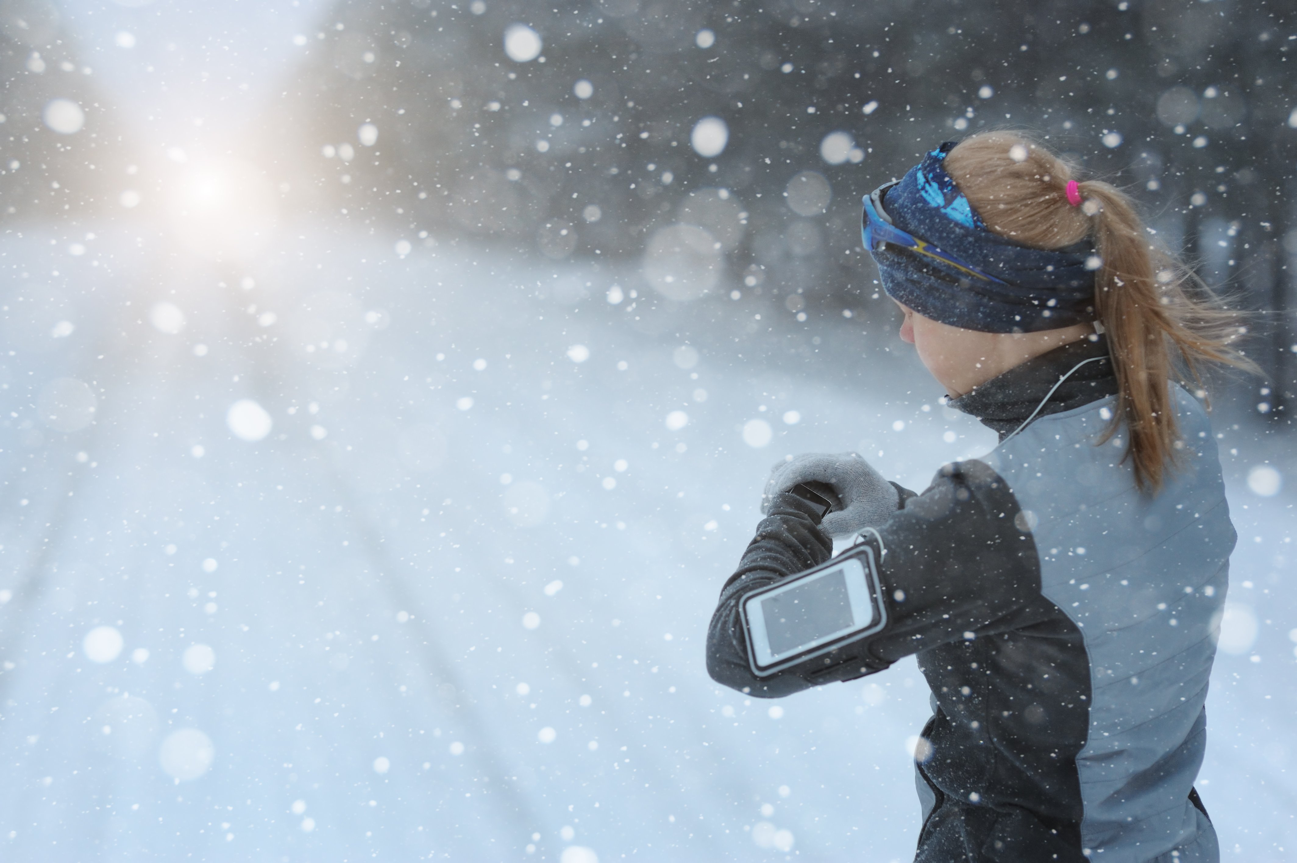 Runner wearing smart phone and watch in snowy conditions