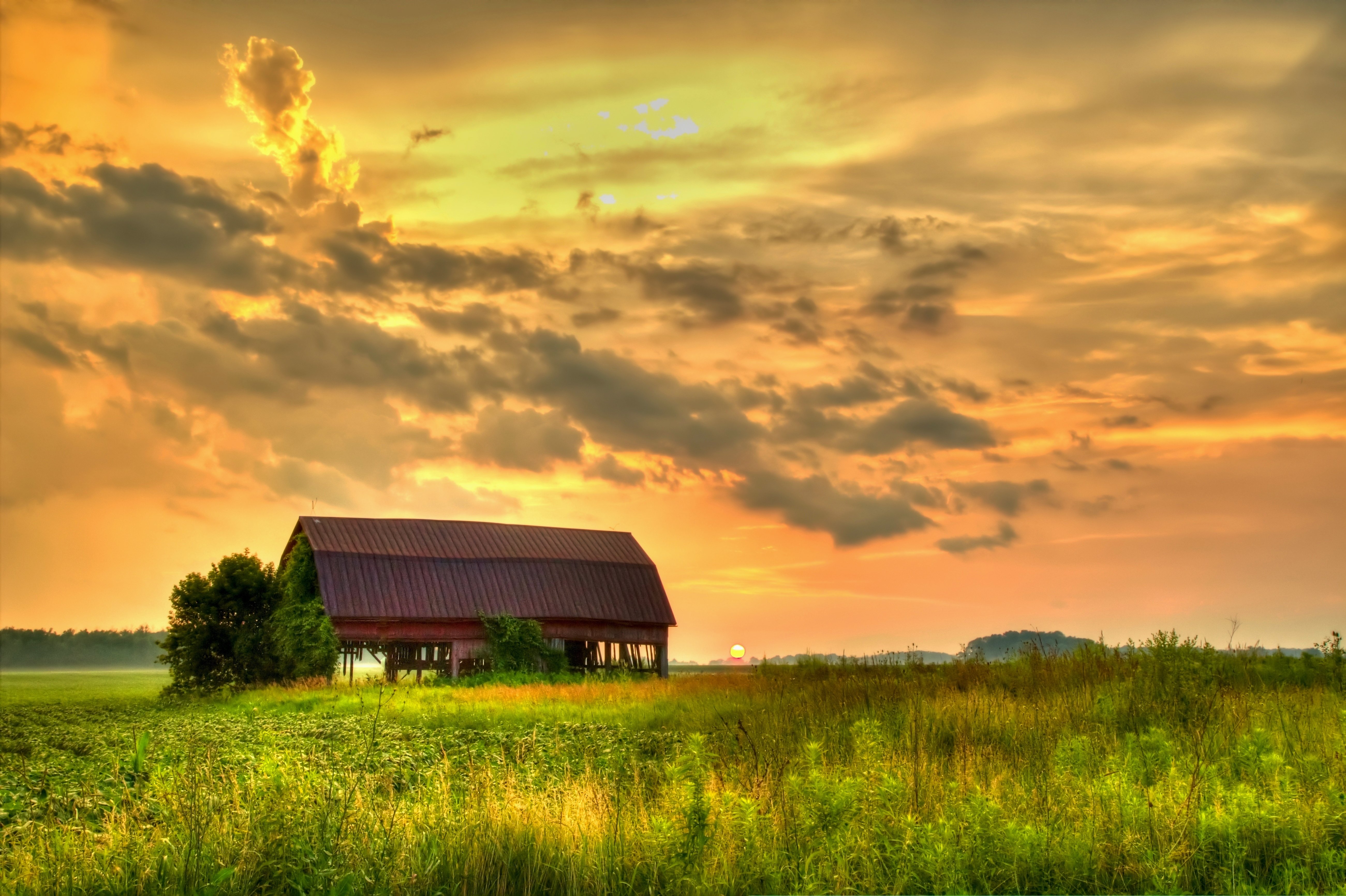 A sunset over a barn structure