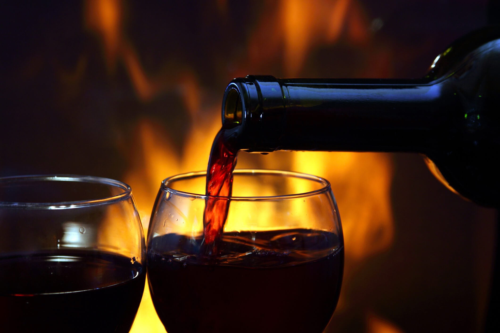 Red wine poured into glasses in front of fireplace