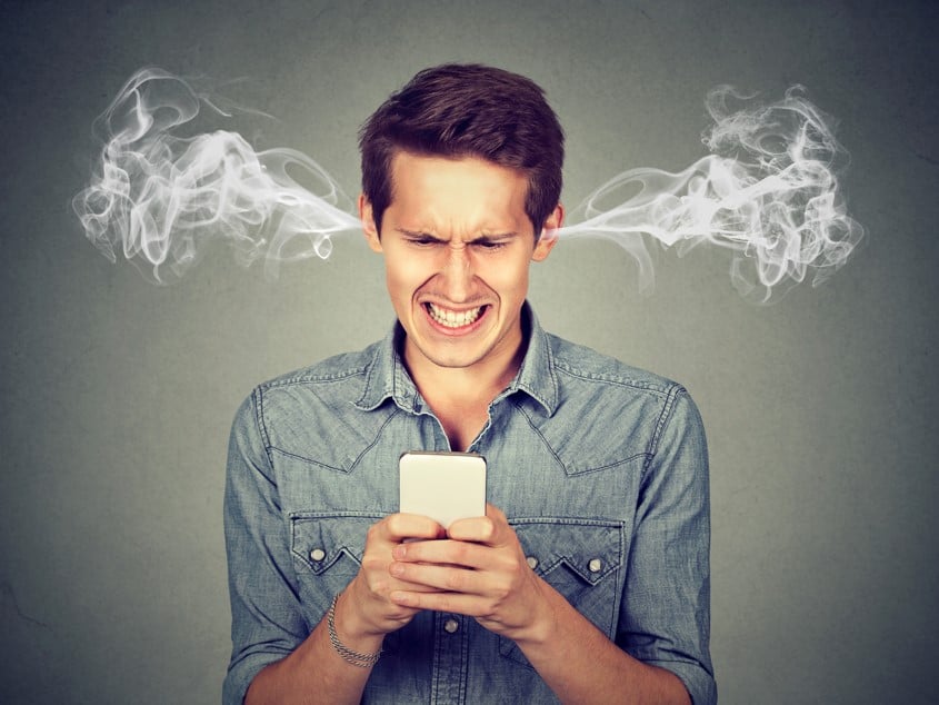 man on smartphone with smoke coming out of ears