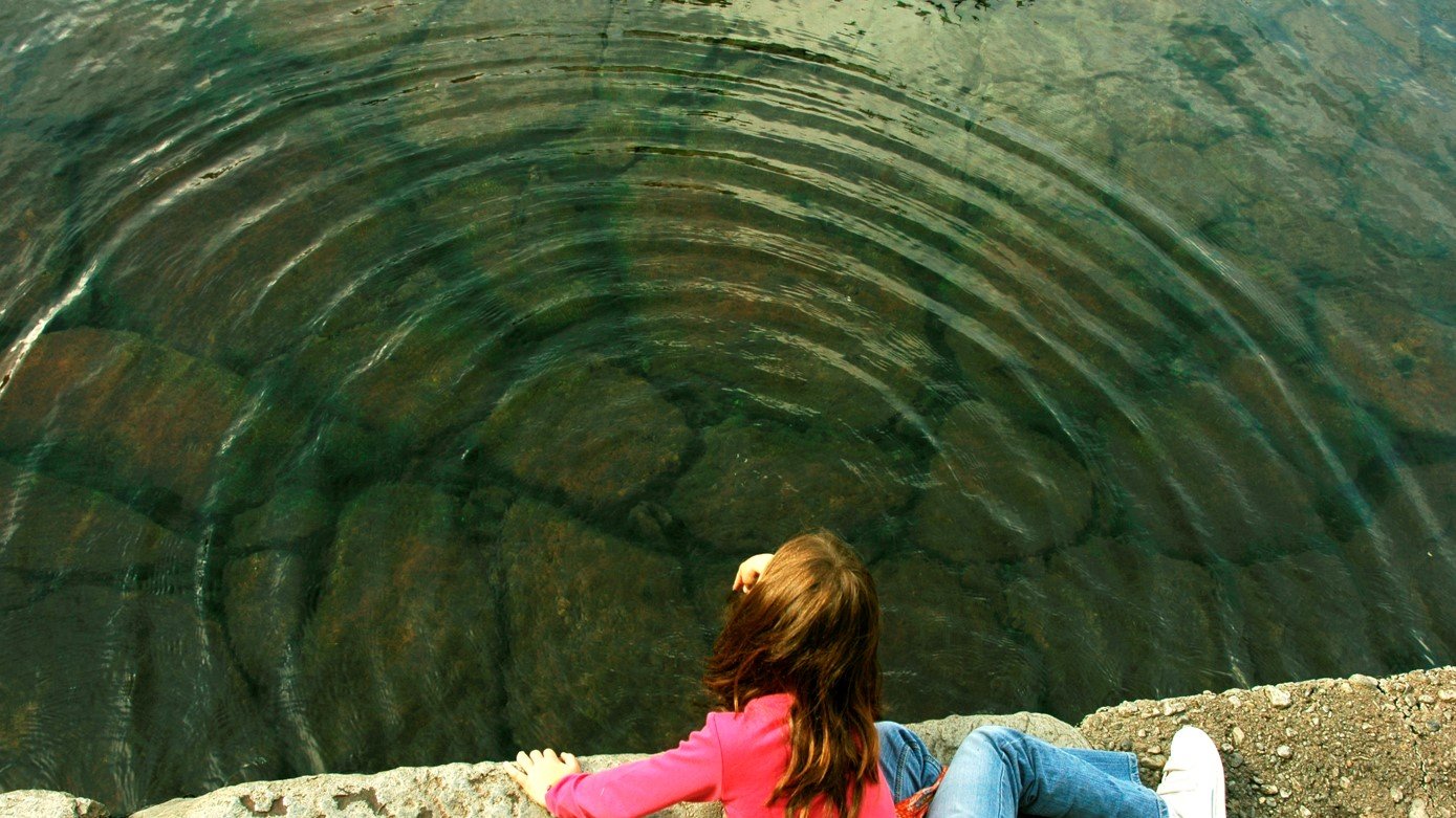 girl at edge of pond with ripples in water