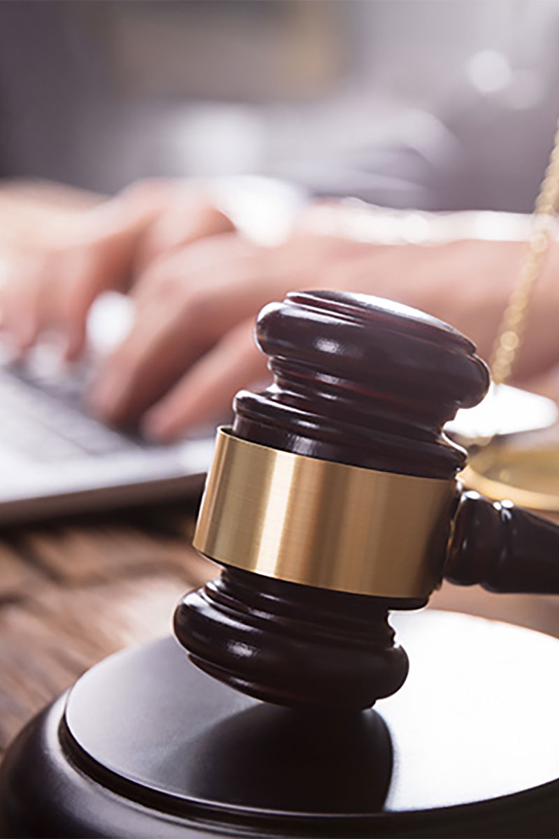 Person typing on laptop next to gavel