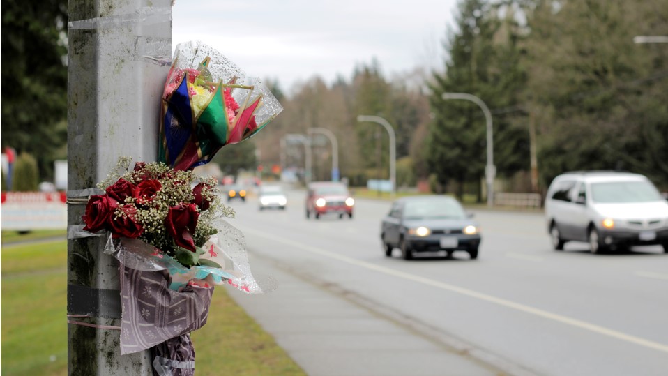 flowers on a roadside pole as a memorial for a traffic fatality