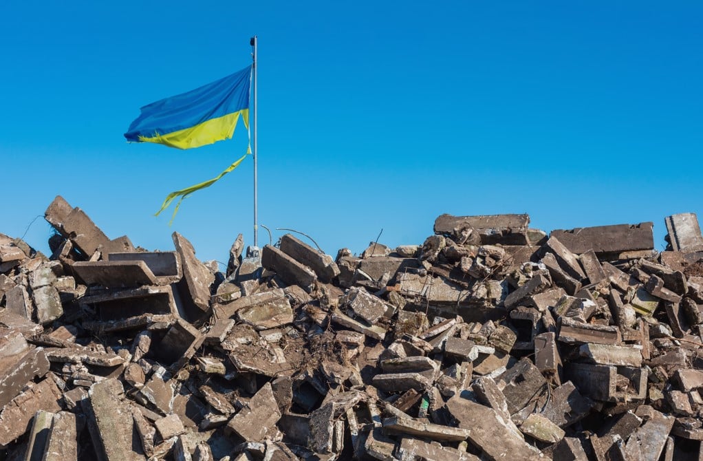 torn ukrainian flag atop rubble