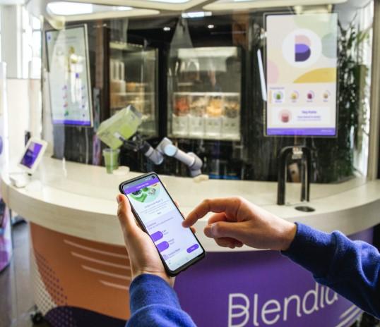Blendid food prep with person on cell phone ordering