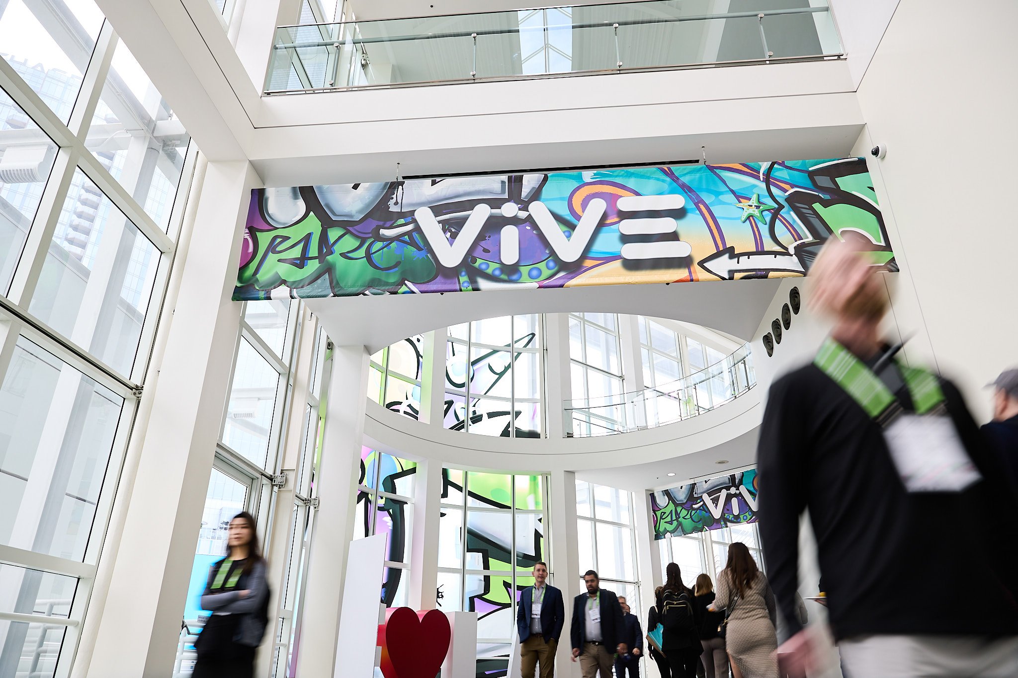 ViVE attendees walk through a convention center hallway under a ViVE banner