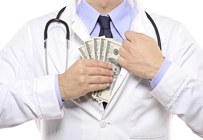 Doctor putting money into his white lab coat
