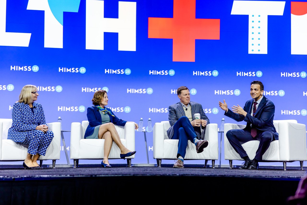 Four healthcare executives sit on a stage during a panel discussion at HIMSS 2023