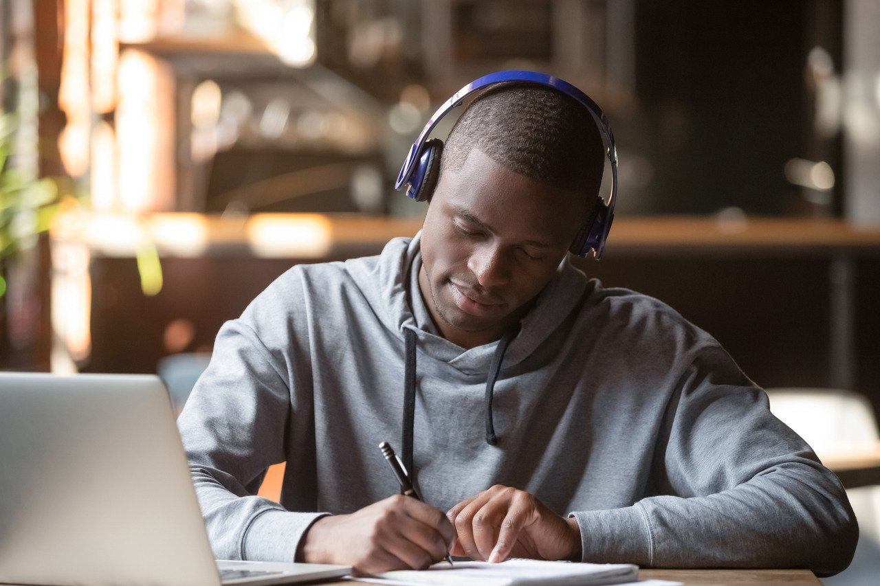 young adult studying at laptop wearing headphones