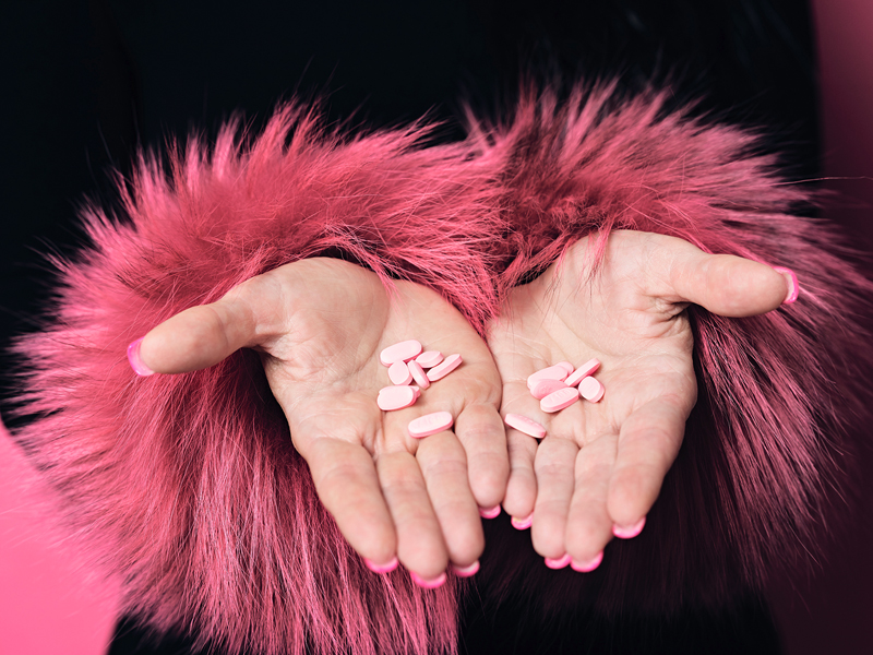 womans hands hold pink pills