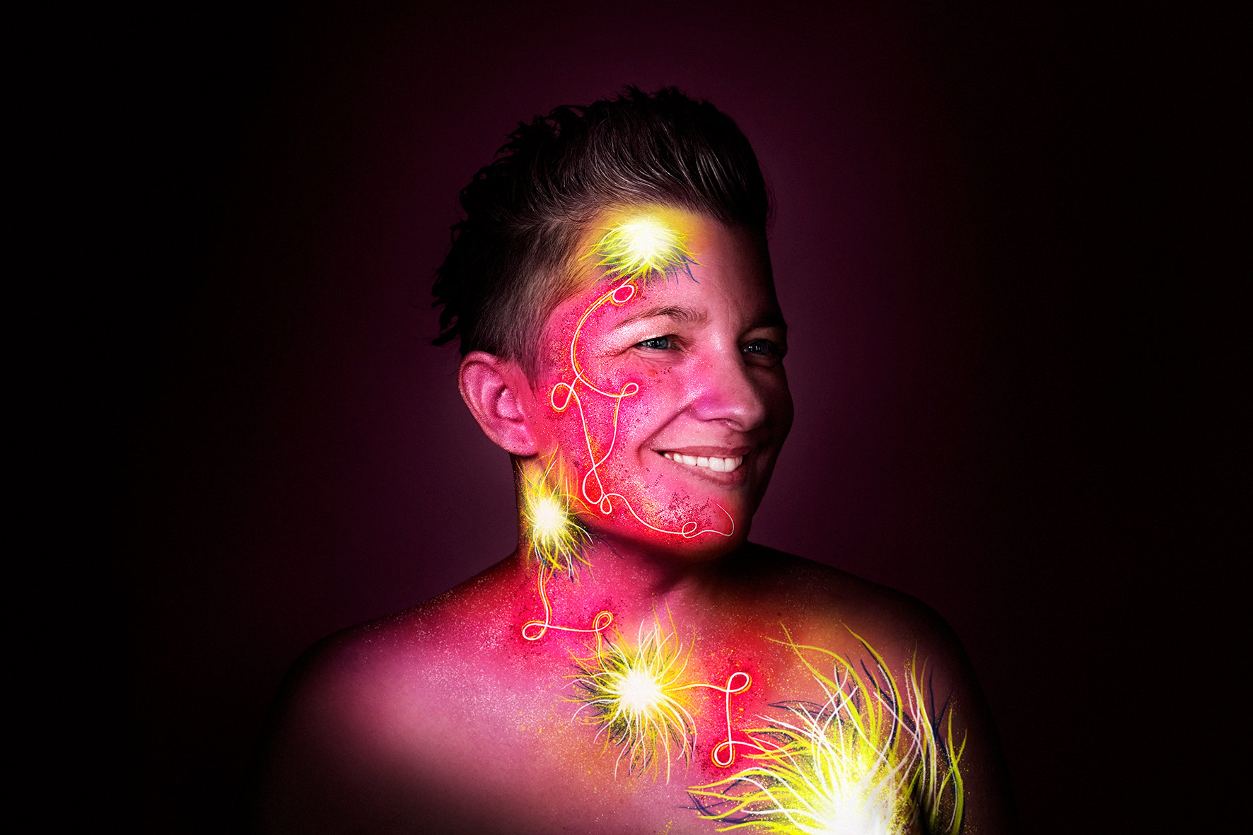 Smiling woman with glowing designs on skin