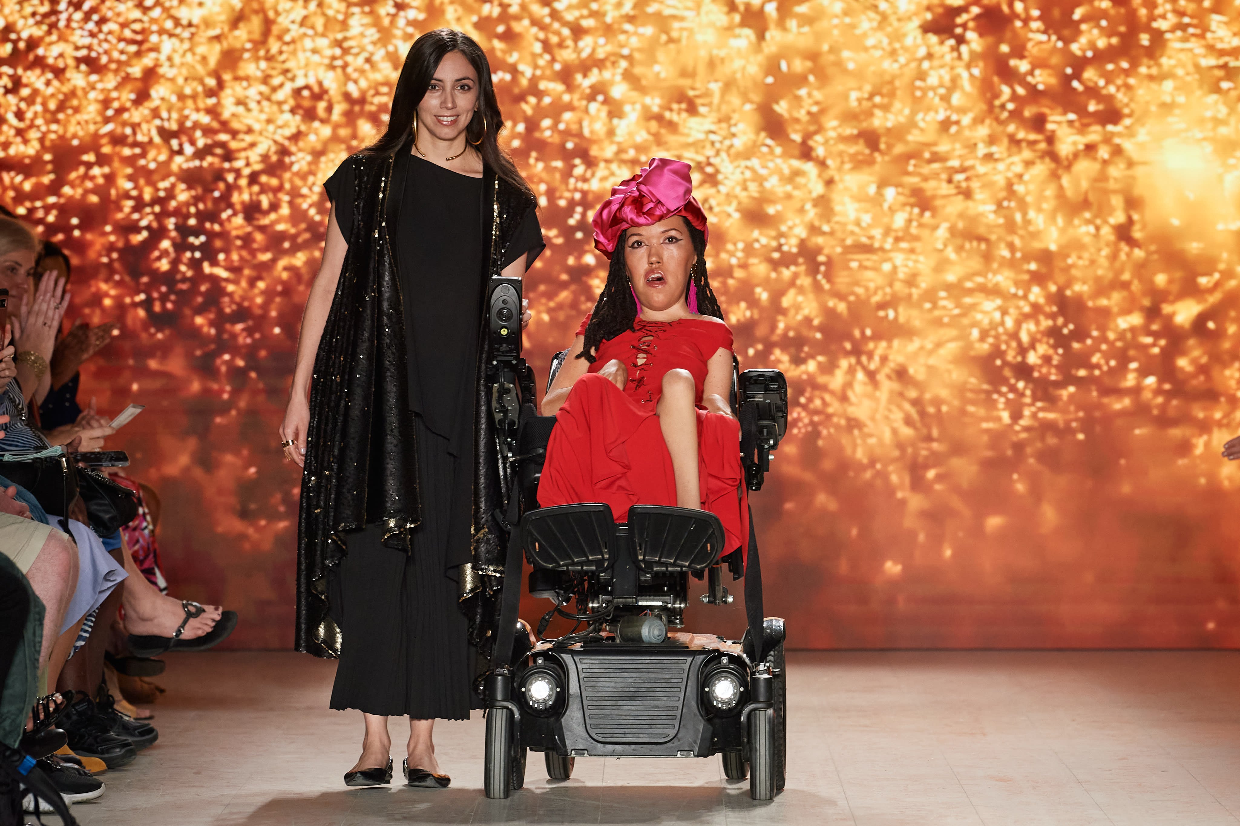 Woman walks with woman in wheelchair down a runway