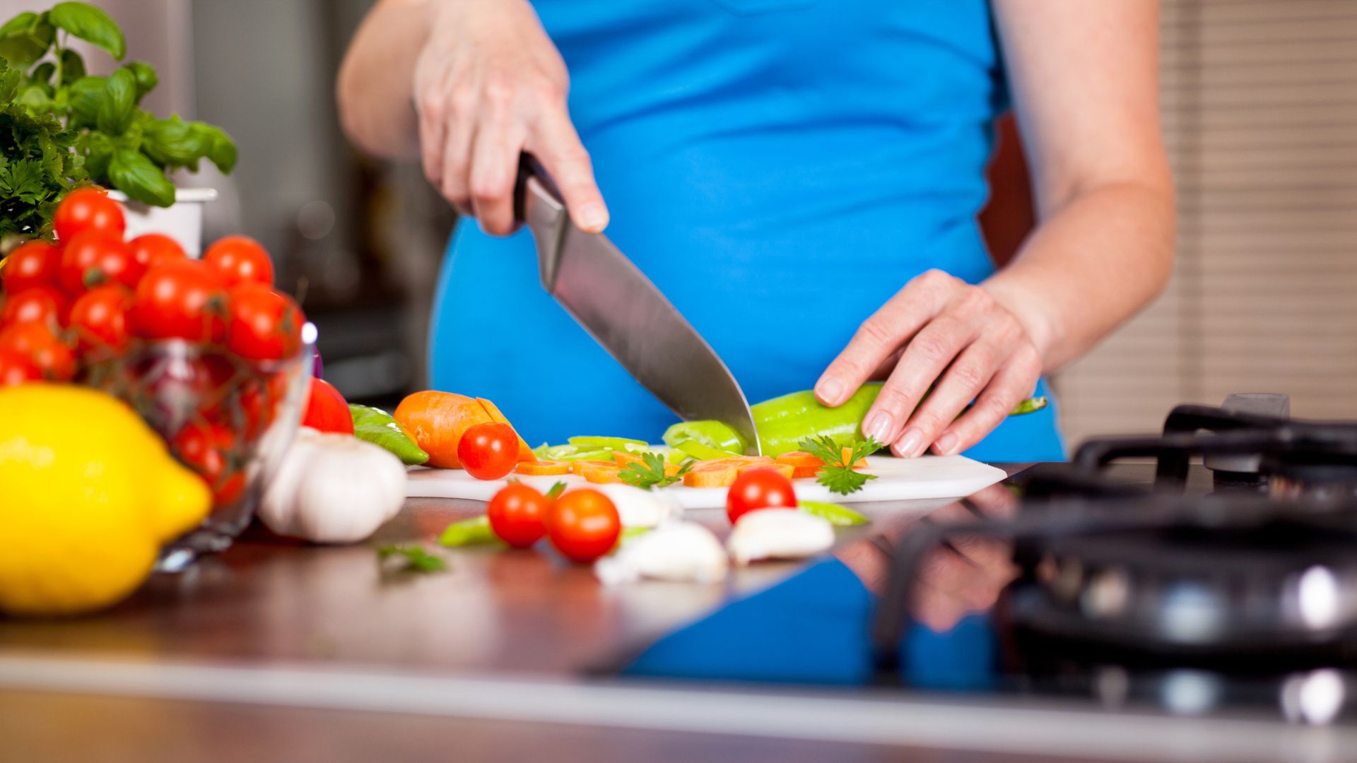 Pregnant woman chopping up fresh vegetables