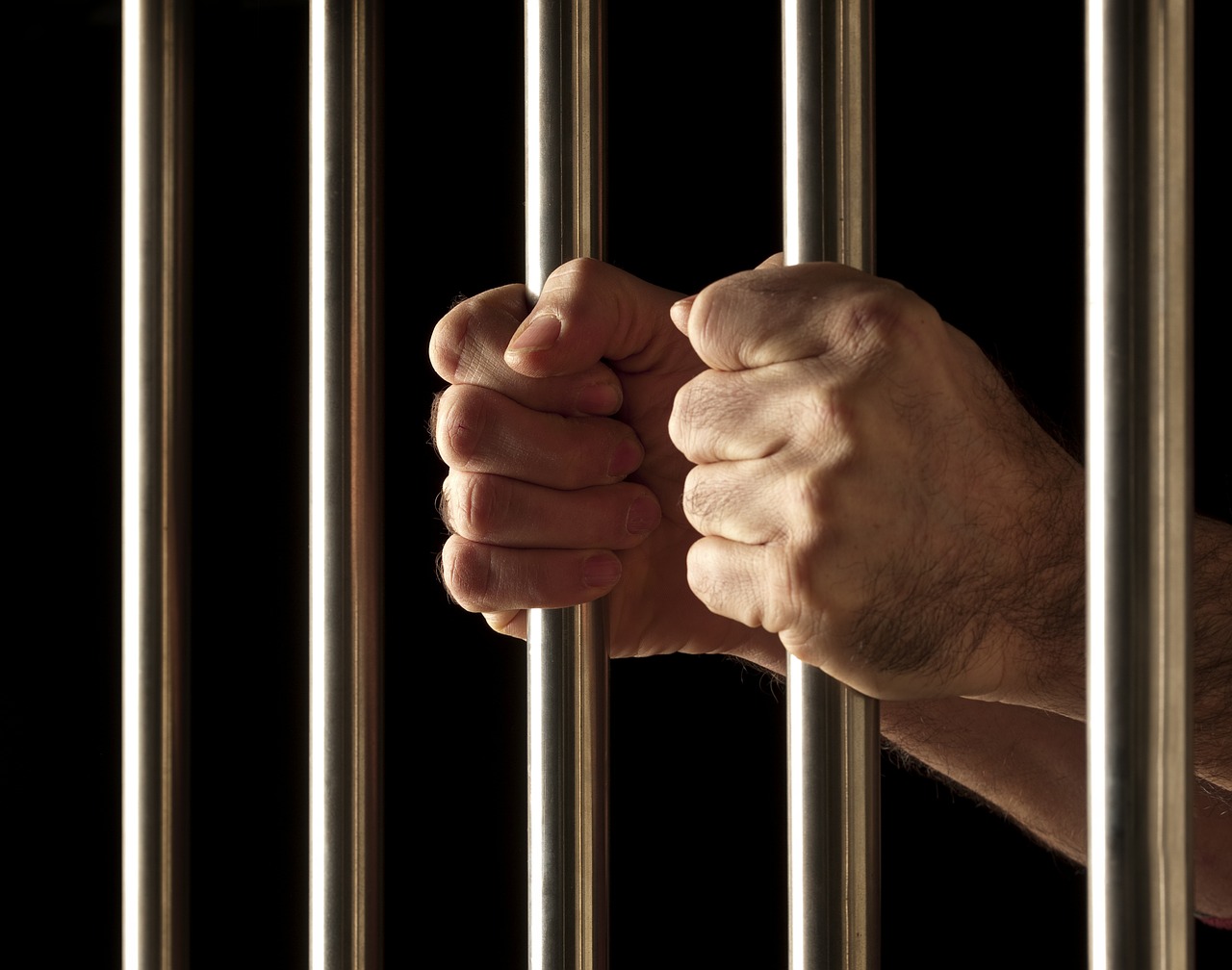 Hands clutching prison bars