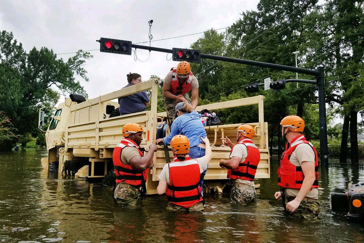 Rescue workers help woman into truck amid floodwaters