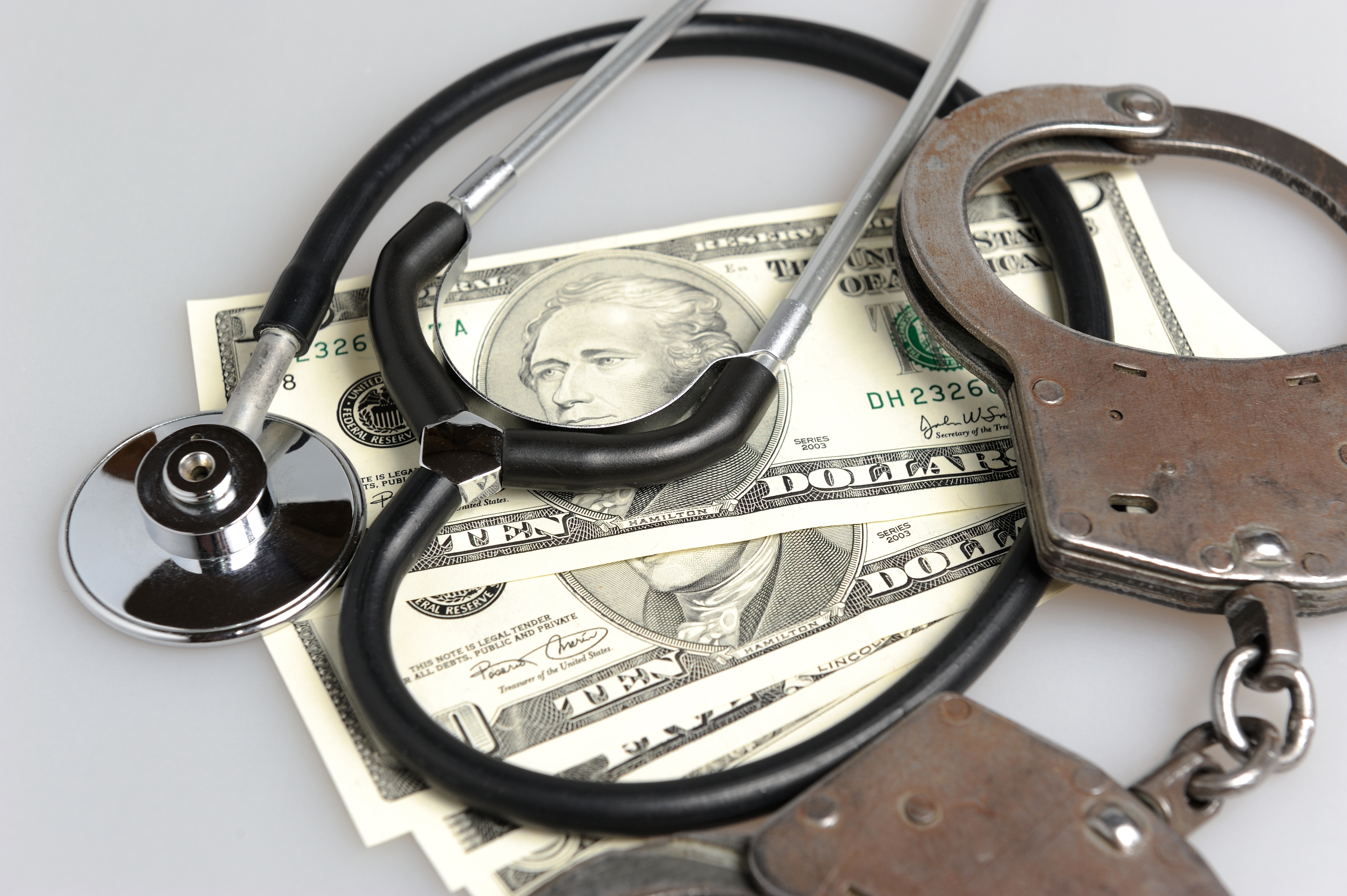 Money handcuffs and a stethoscope 