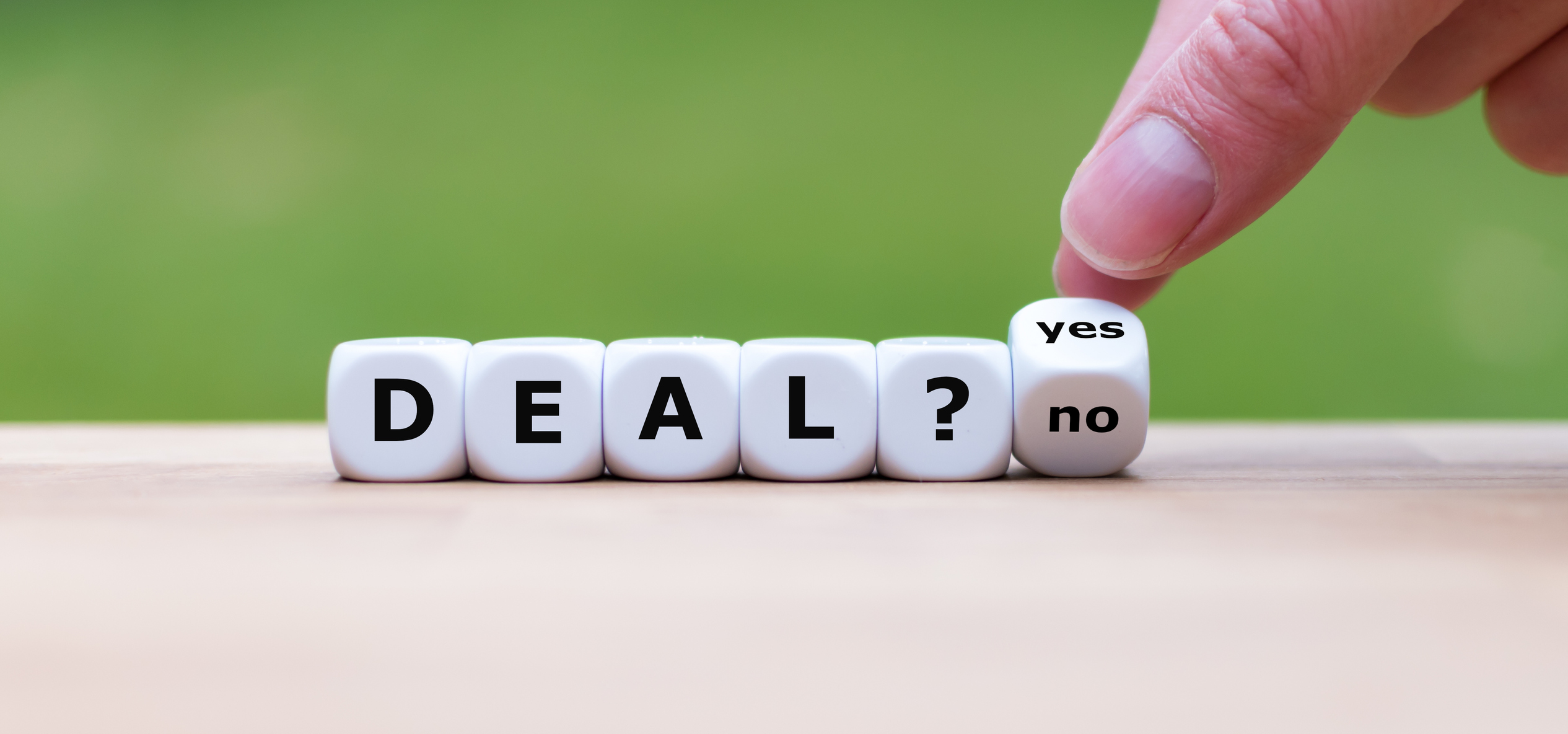 photo of deal spelled out using dice with a final dice teetering between yes or no