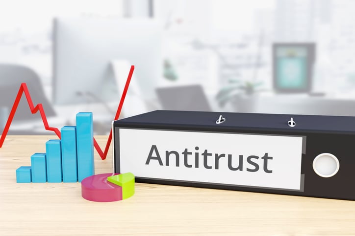 A folder that says antitrust next to financial graphs on a table