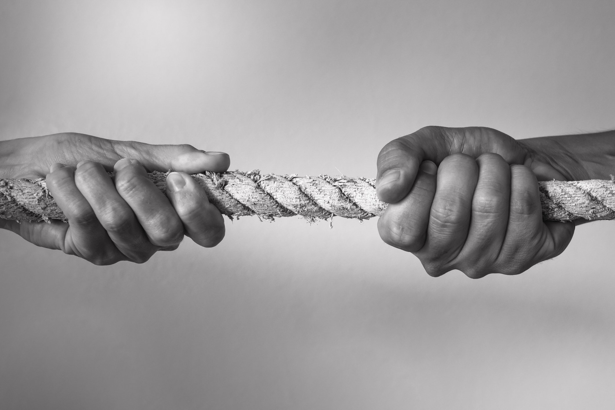 Two hands gripping onto a rope seemingly tugging in opposite directions