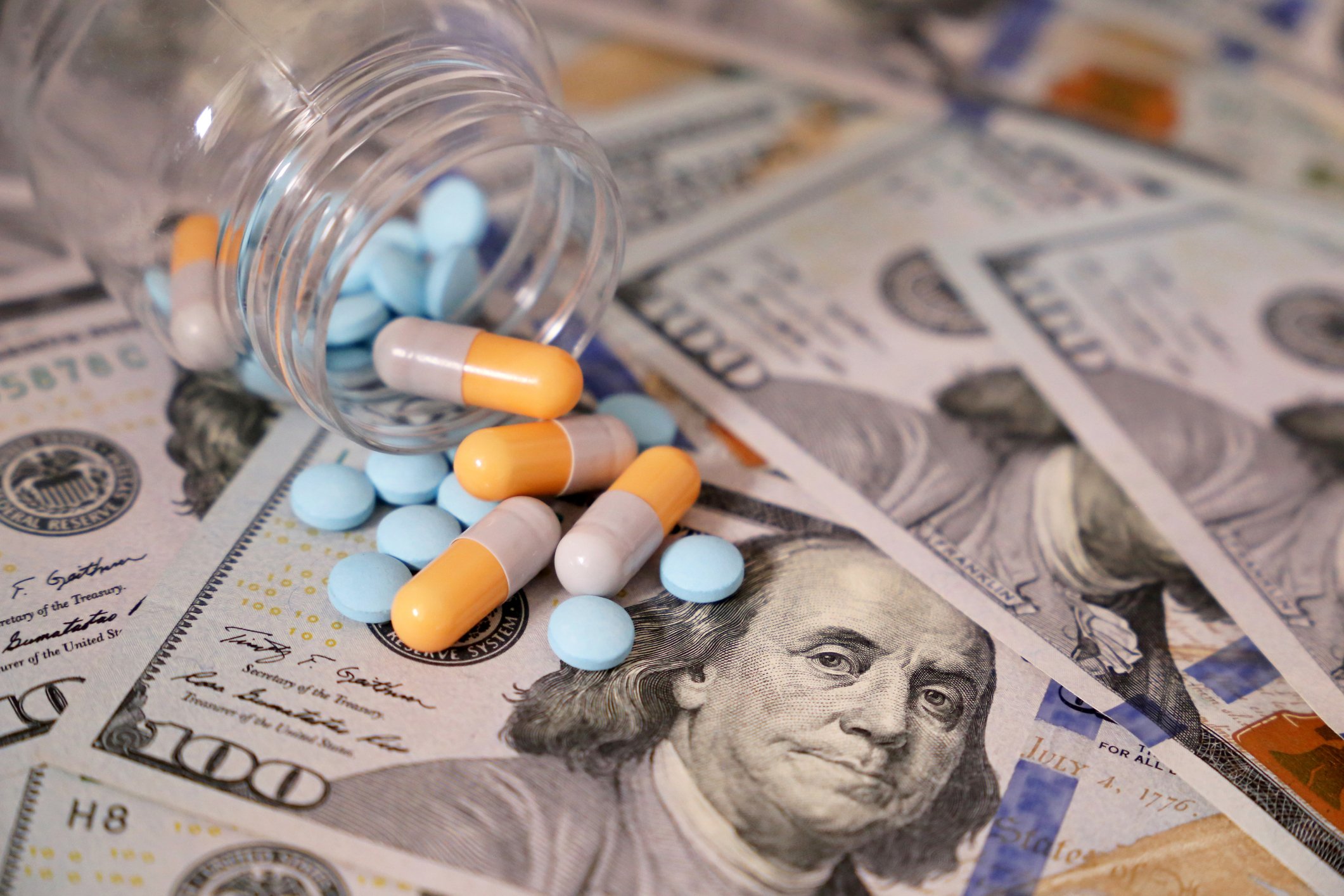 Pills and capsules in a bottle on US dollars bills