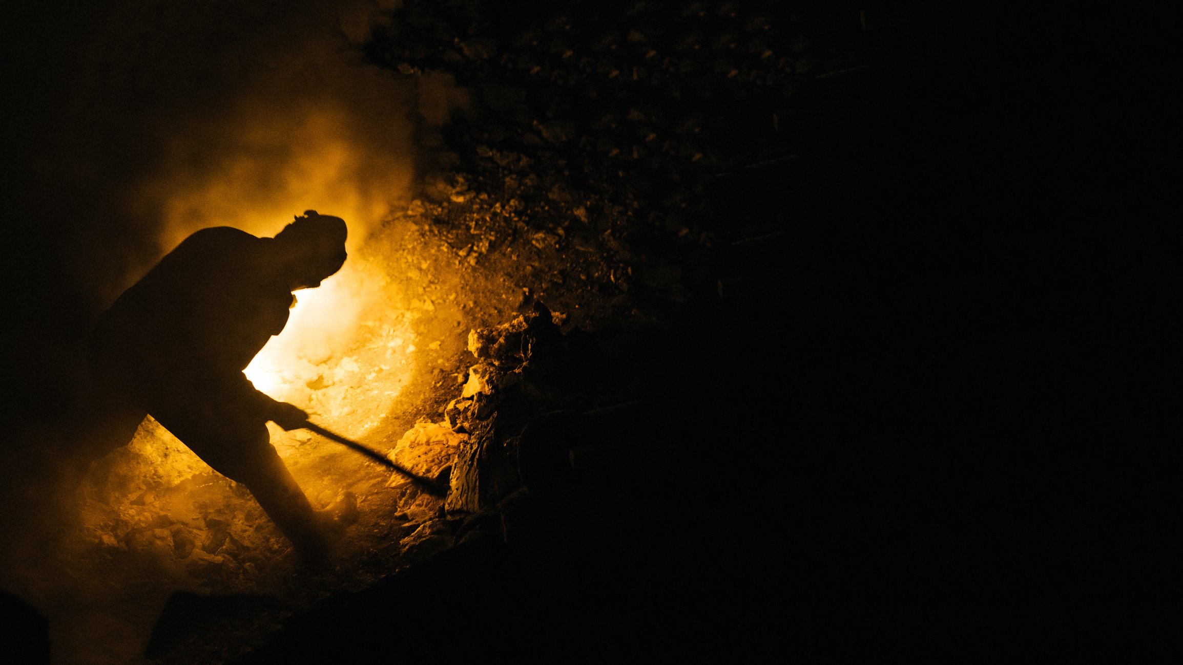 The silhouette of a miner digging