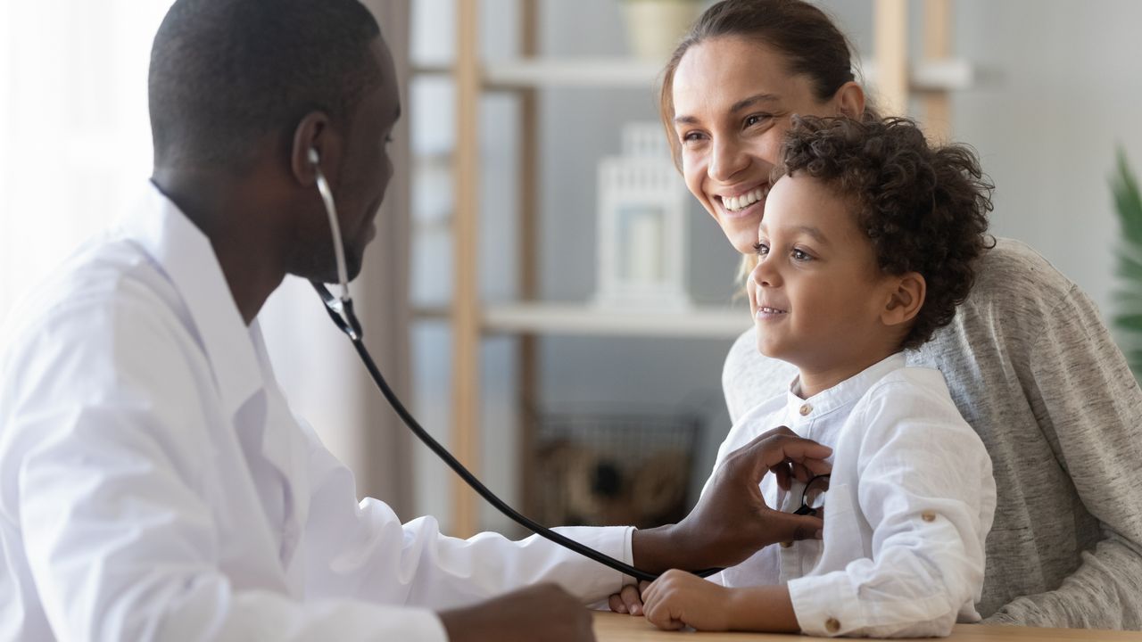 Male pediatrician hold stethoscope to exam a child patient during visit with mother
