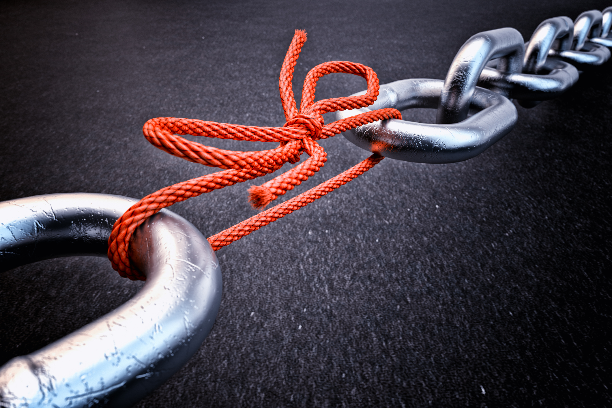 Photo of a chain being held together by a piece of rope