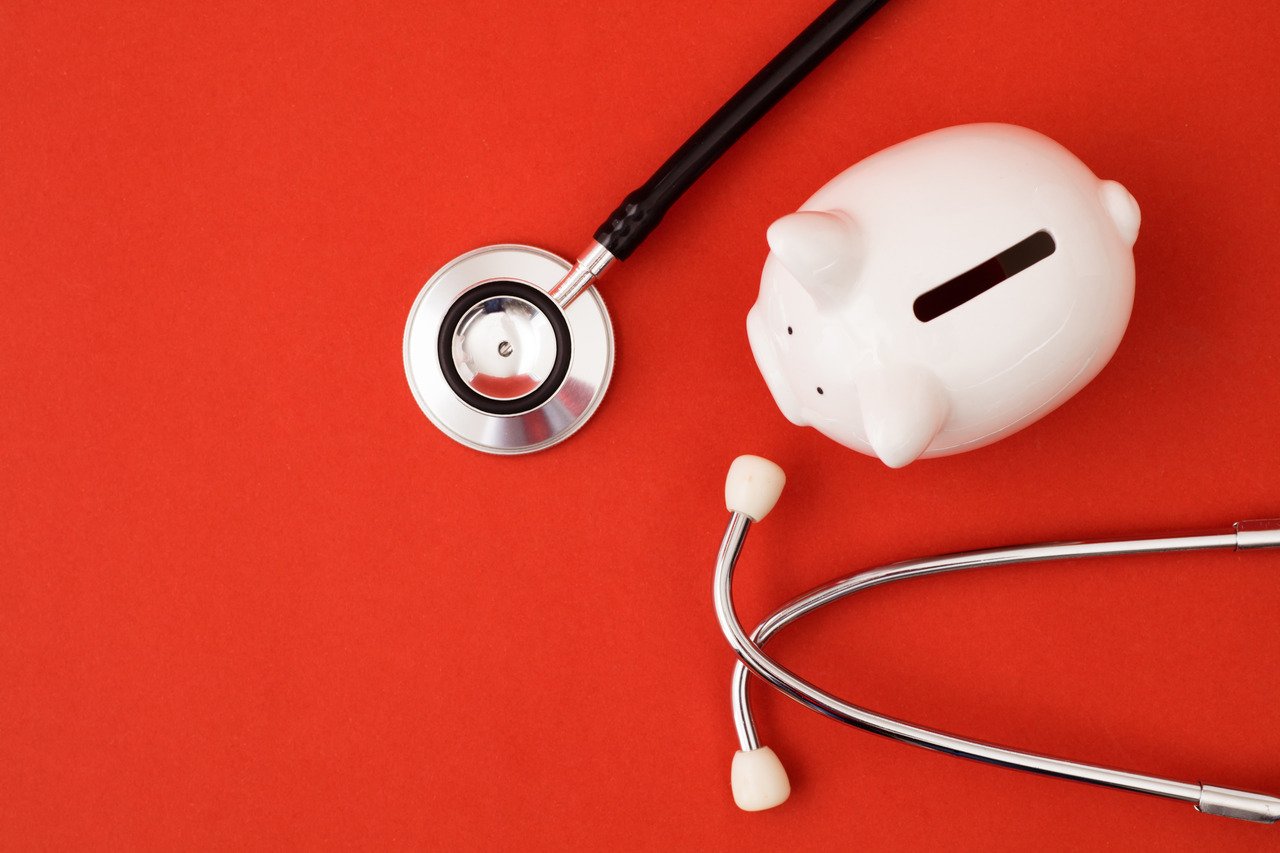 piggy bank with stethoscope on red background