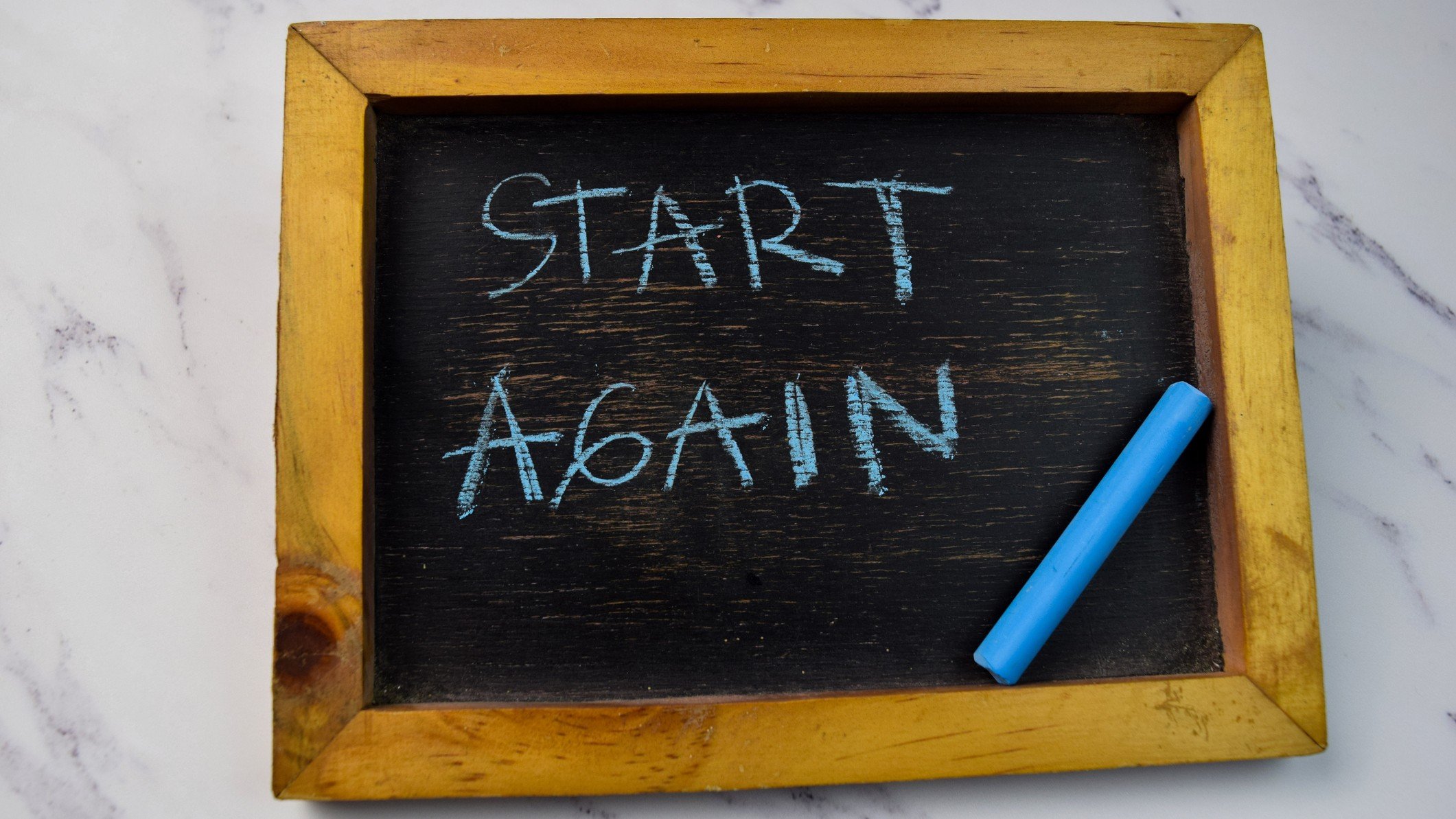 Start Again written on a chalkboard on wooden table 