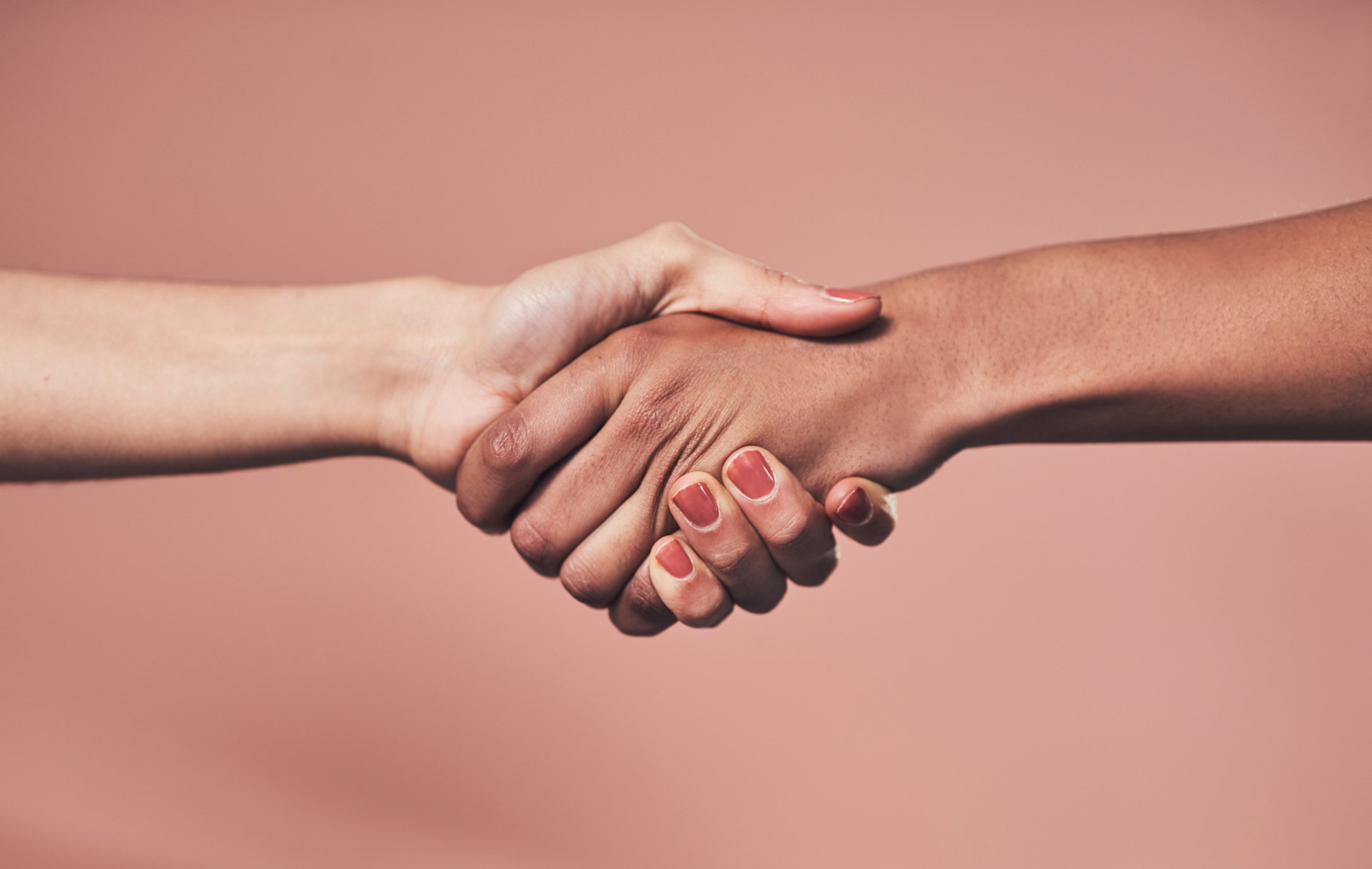 photo of two people shaking hands one of which has red nail polish on