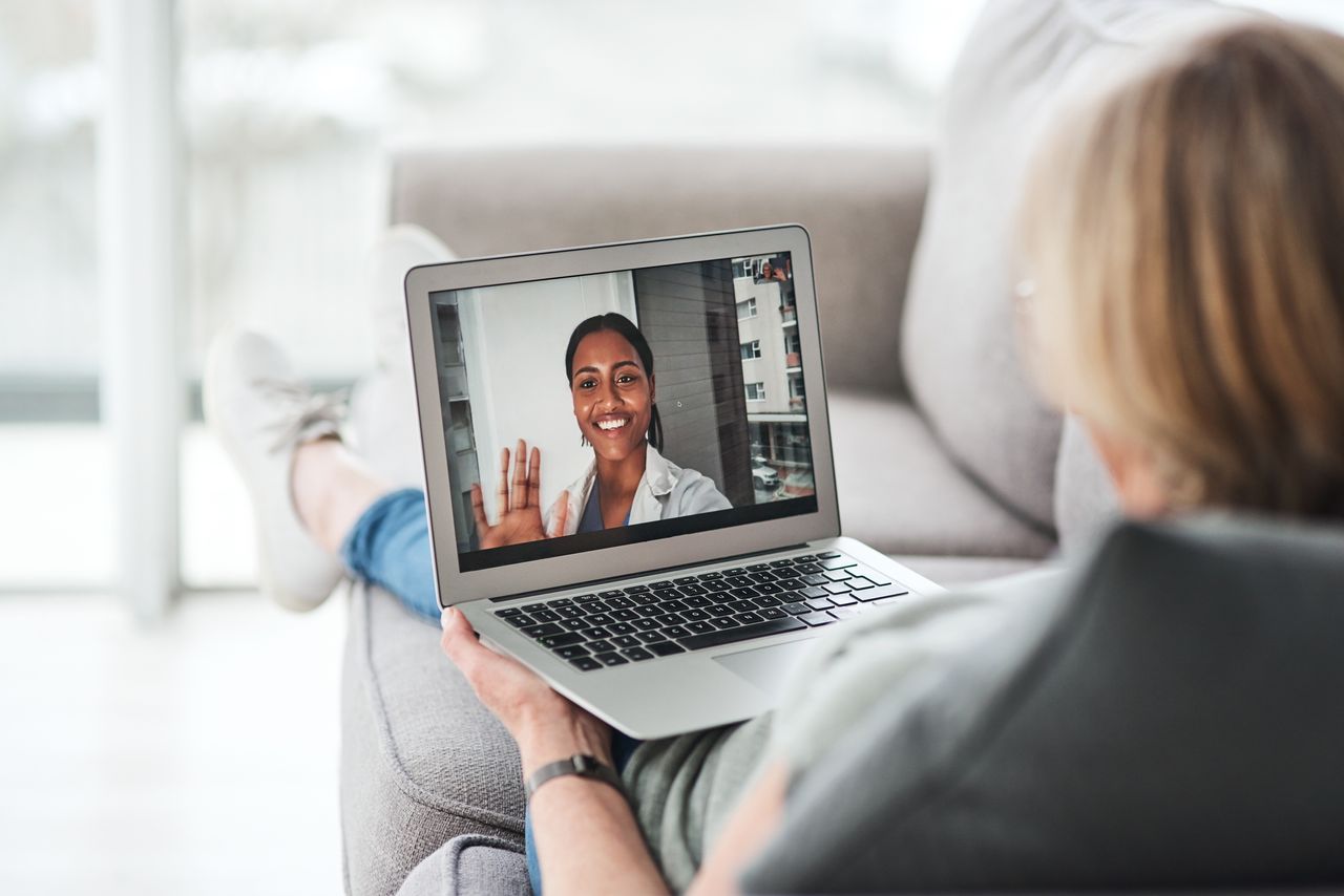 Shot of a senior woman using a laptop to make a video call with her doctor on the sofa a home