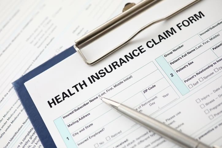 A clipboard with a health insurance claim form and a silver pen
