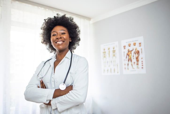 A black female doctor poses in an exam room