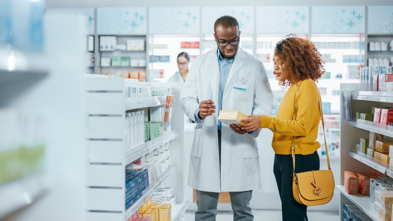 A male pharmacist assists a female patient